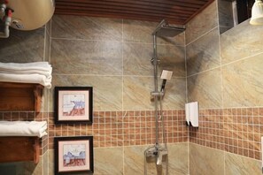 Un bagno con doccia, pareti piastrellate, quadri appesi e asciugamani.