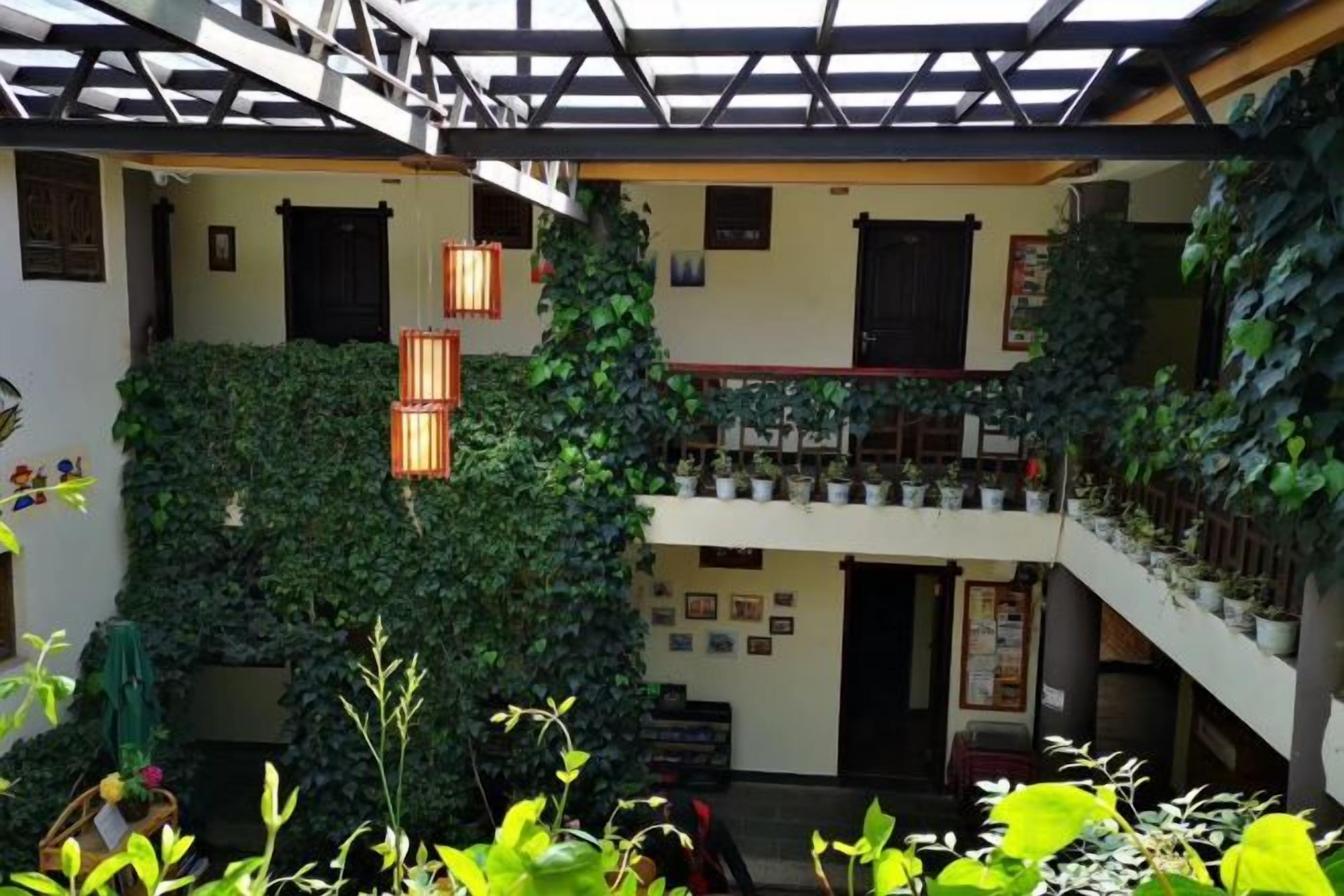 A multi-level atrium with a staircase, potted plants, and hanging lanterns.