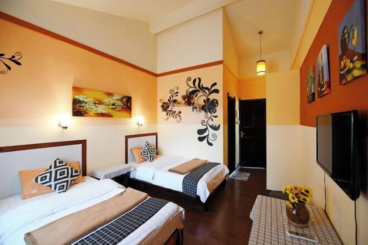 A hotel room with two beds, a TV, a painting, and a decorative wall piece.