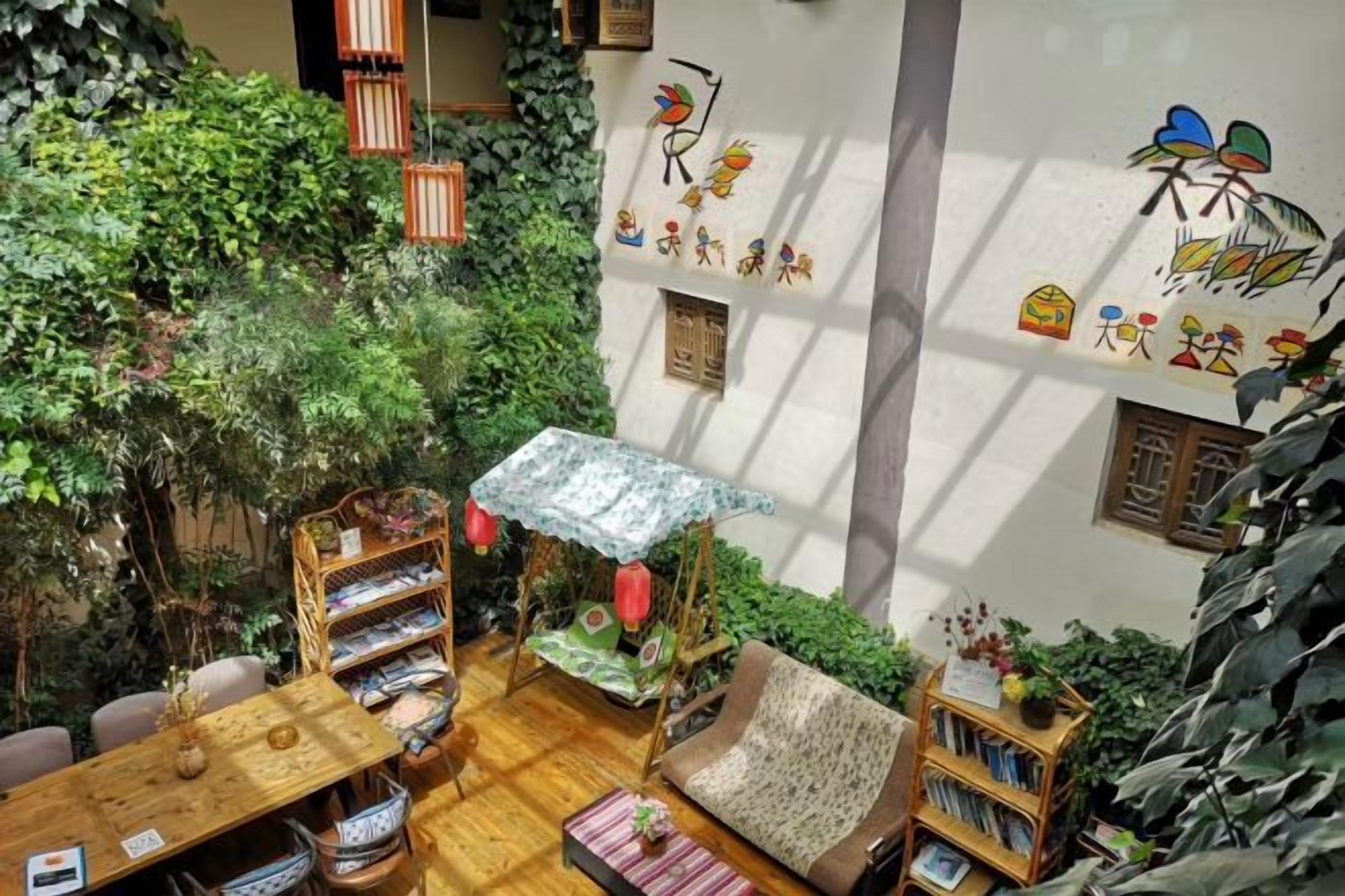 A cozy indoor space with a wooden table, chairs, a patterned sofa, and a small garden area with plants and a decorative umbrella.