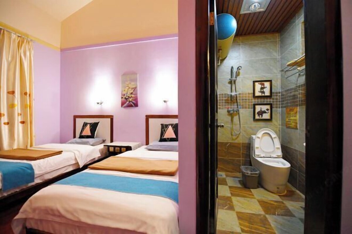 A hotel room with two beds, a bathroom with a shower, and a toilet.