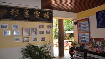 A reception area with a wall displaying framed pictures, a potted plant, and a wooden ceiling.
