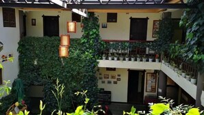 Un atrio de varios niveles con techo de vidrio, plantas verdes exuberantes y macetas en los balcones.
