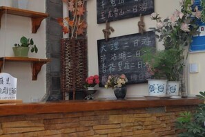 A reception area with a stone wall, wooden shelves, and potted plants. - Maple Leaf Inn Lijiang (Lijiang)