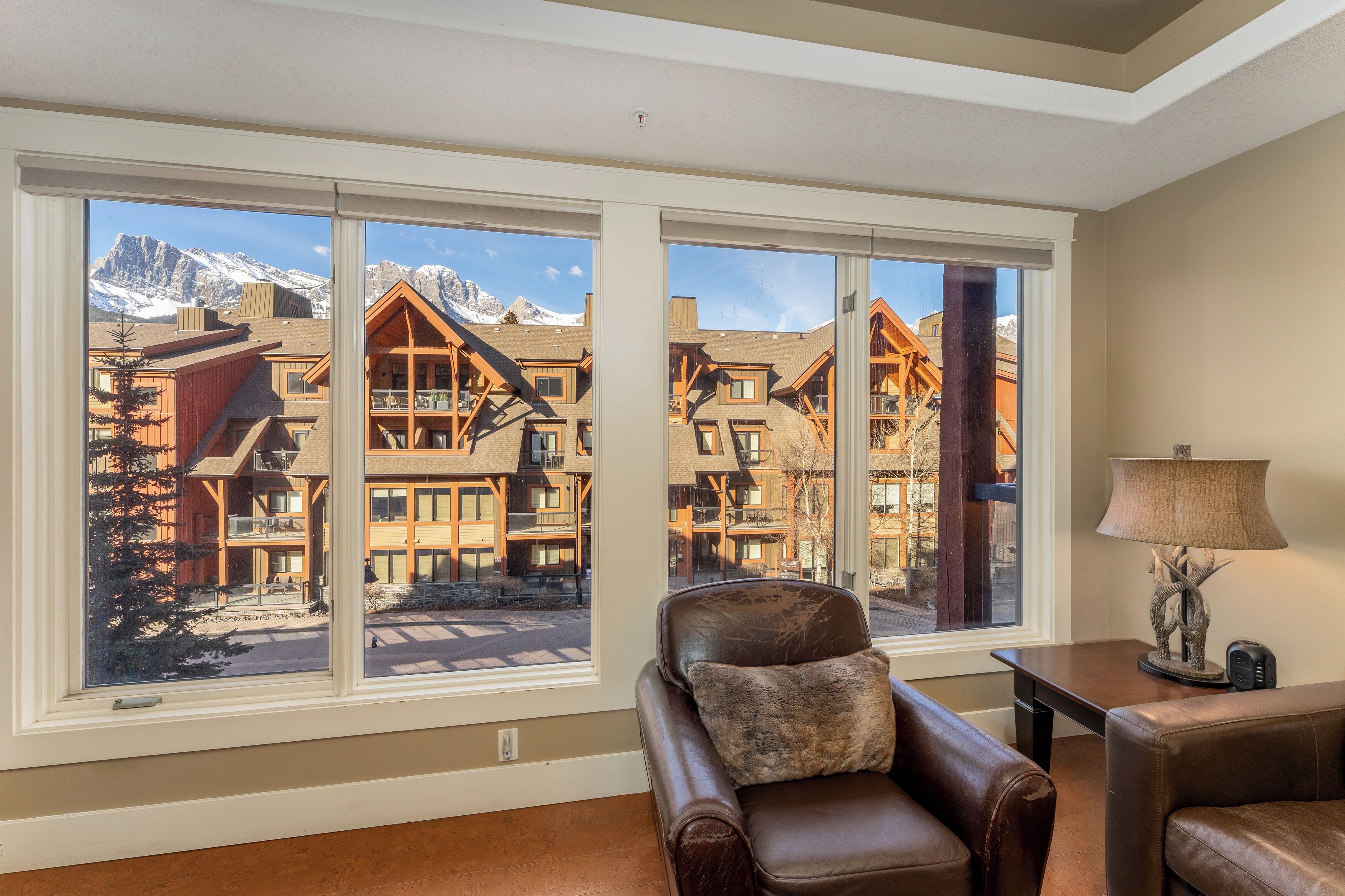 A room with large windows offering a view of a mountain lodge.