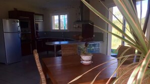 A kitchen with a dining table, chairs, and a potted plant.