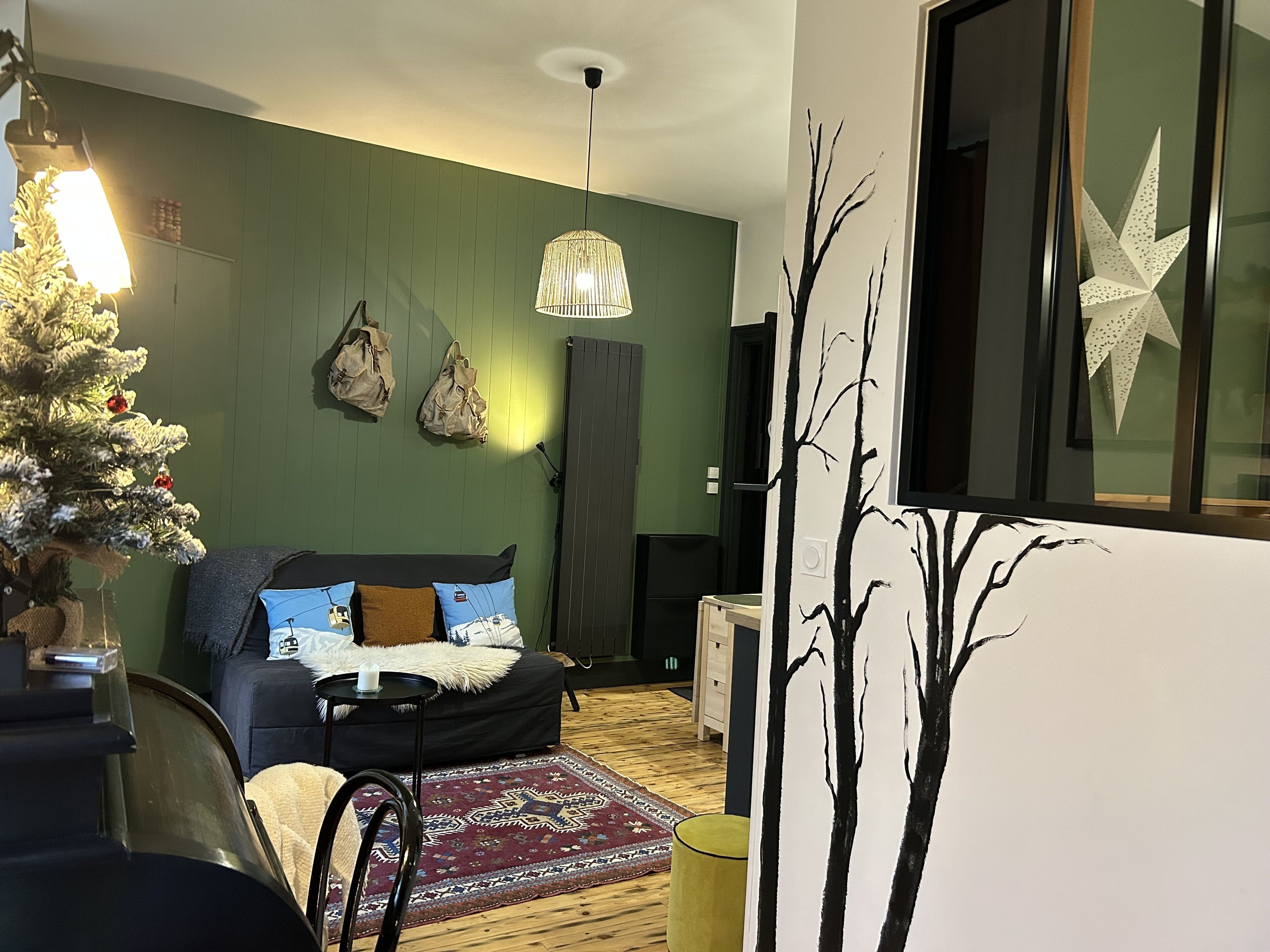 Una stanza accogliente con un letto, un albero di Natale e un'ampia finestra decorata con una stella.