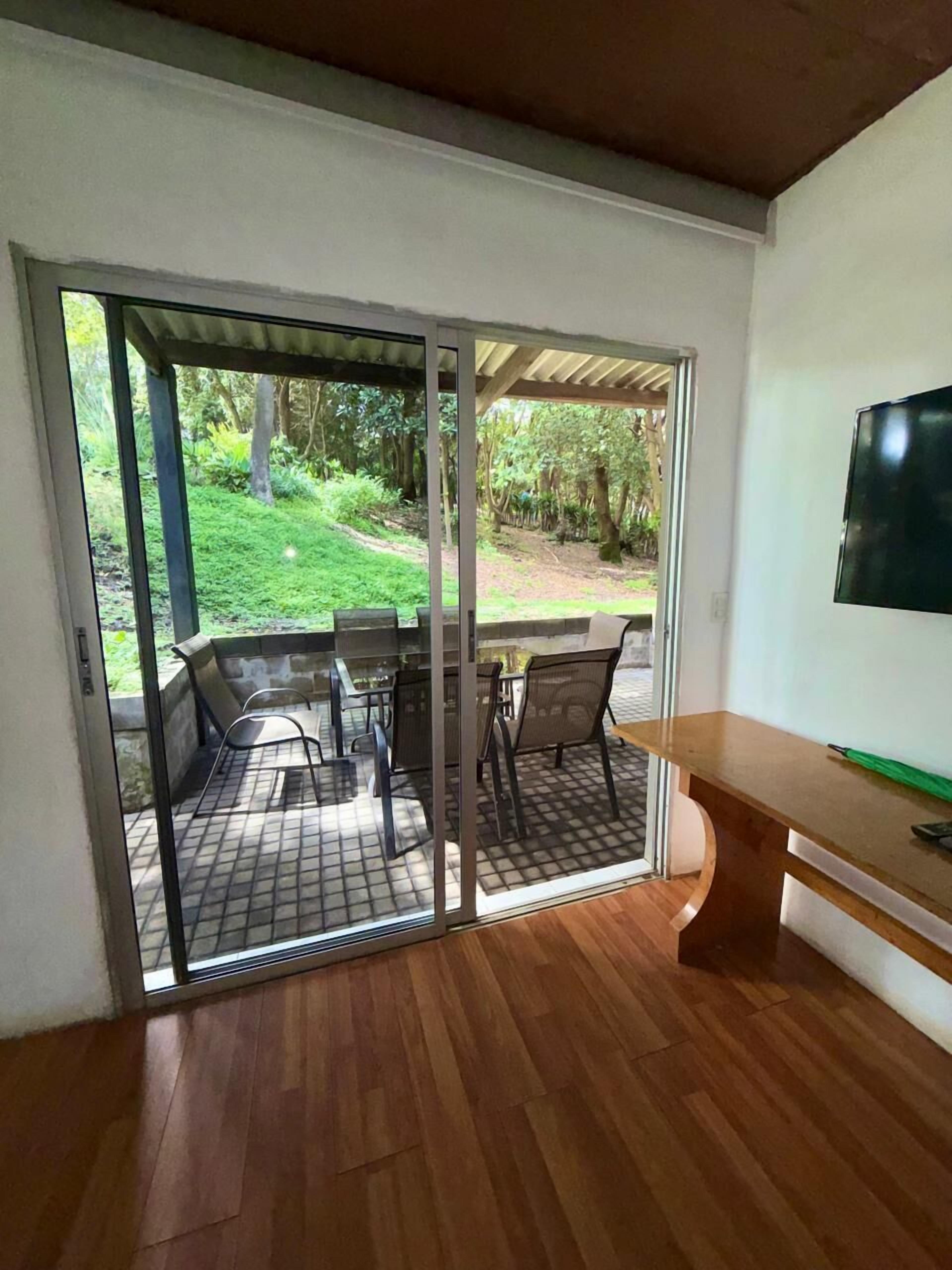 Een kamer met een schuifdeur naar een terras buiten, compleet met een tafel en stoelen.