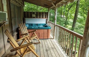 Relax on the deck with a hot tub and two comfortable rocking chairs, surrounded by a lush forest view.