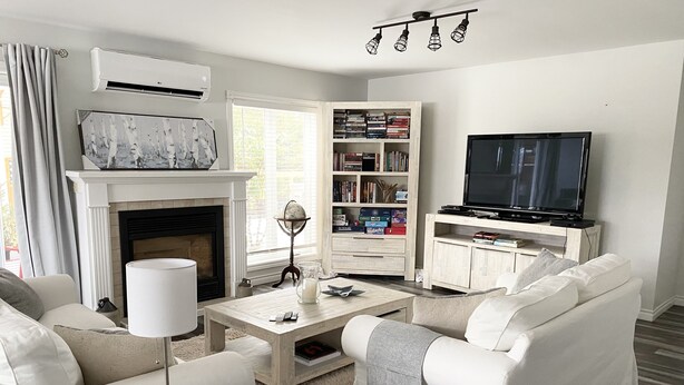 Ein Wohnzimmer mit Kamin, Fernseher, Bücherregal und Couchtisch.
