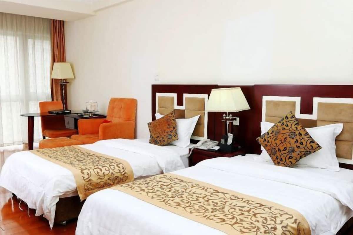 Ein Hotelzimmer mit zwei Betten, einem Schreibtisch und einem Stuhl.