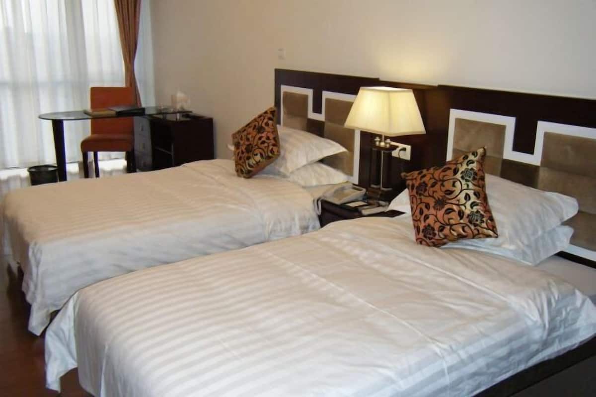 Ein Hotelzimmer mit zwei Betten, einem Schreibtisch, einem Stuhl und einer Lampe.