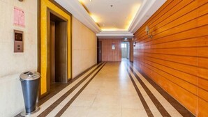 A hotel corridor with a trash bin, an elevator, and a wooden wall. - Kunshan Youjia Jitian Apartment (Kunshan South Station) (Kunshan)