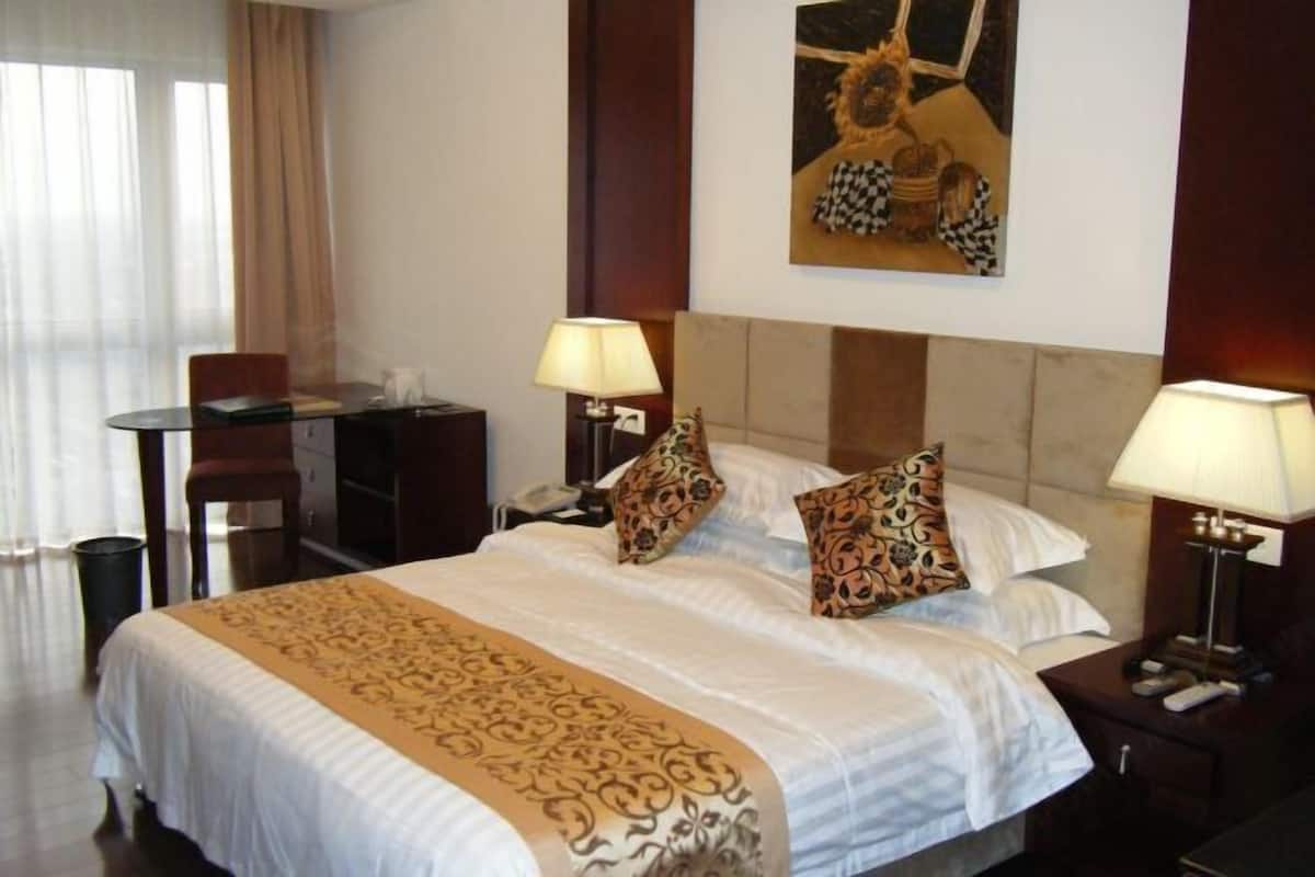 Ein Hotelzimmer mit einem Bett, zwei Nachttischen, einem Schreibtisch und einem Stuhl.