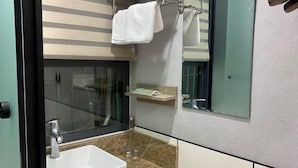A bathroom with a white sink, a glass shower enclosure, and a mirror with a towel hanging on it. - Beicheng Hotel (Dazhu)