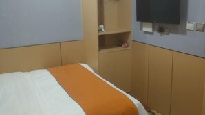A hotel room with a bed, a television mounted on the wall, and a wardrobe with a mirror. - Beicheng Hotel (Dazhu)