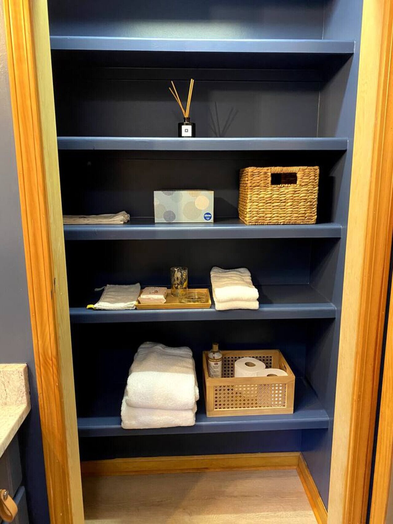 A blue shelving unit with various items including a box, a basket, and folded towels.