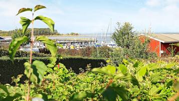 A marina with boats docked, a red building, and lush greenery in the foreground.