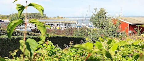 Un puerto deportivo con barcos amarrados, un edificio rojo y exuberante vegetación en primer plano.