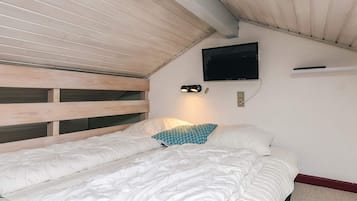 A bedroom with a bunk bed, a flat-screen TV mounted on the wall, and a bedside lamp.