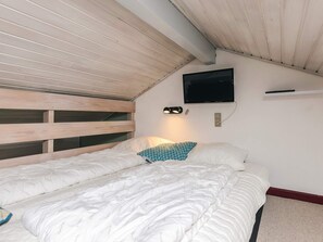 A bedroom with a bunk bed, a flat-screen TV mounted on the wall, and a bedside lamp. - 4 Person Holiday Home in Aeroskobing (Aeroskobing)