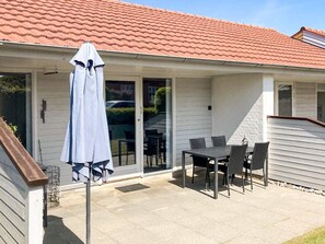 A patio with a table and chairs, a covered umbrella, and a red-tiled roof. - 4 Person Holiday Home in Aeroskobing (Aeroskobing)