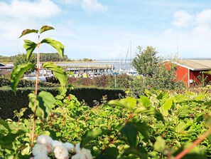 A marina with boats docked, a red building, and lush greenery in the foreground. - 4 Person Holiday Home in Aeroskobing (Aeroskobing)