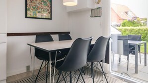 Een eetruimte met een tafel, stoelen, een hangende lamp, een wandklok en een lijst met een kaart.