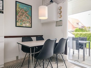 A dining area with a table and chairs, a hanging light fixture, a wall clock, and a framed map. - 4 Person Holiday Home in Aeroskobing (Aeroskobing)