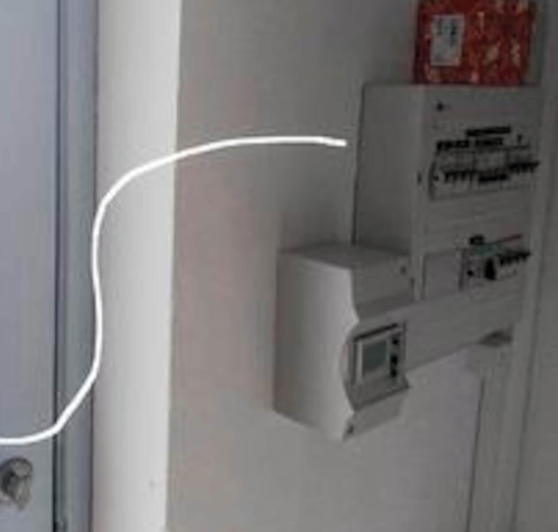 A wall-mounted electrical panel with a keyhole, a small display screen, and a red emergency phone.