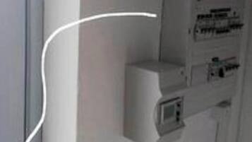 A wall-mounted electrical panel with a keyhole, a small display screen, and a red emergency phone.