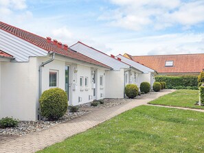 A row of white buildings with red-tiled roofs, a paved pathway, and neatly trimmed hedges. - 4 Person Holiday Home in Aeroskobing (Aeroskobing)