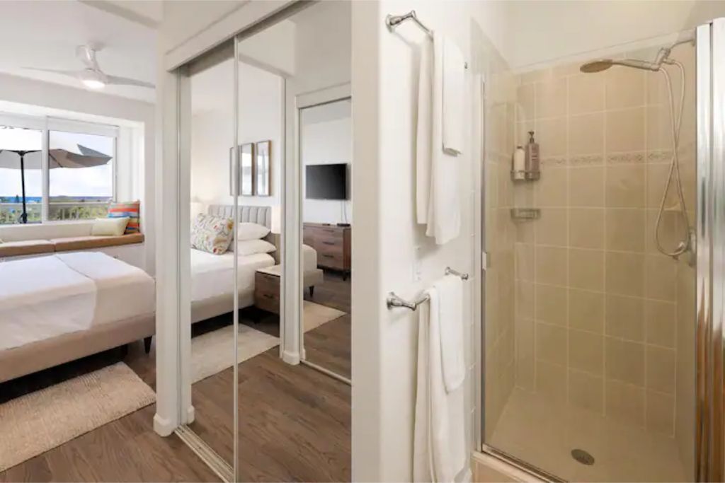 Un dormitorio moderno con cama, sofá, televisión y baño con ducha.