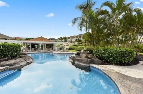 Relax by the clear pool surrounded by lush greenery and natural rock formations.