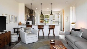 Un salon moderne avec un canapé, une table basse et un téléviseur. Il y a également un coin cuisine avec une table à manger et des chaises.