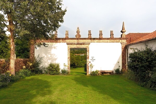 Un edificio tradicional con fachada blanca y tejado de tejas, que presenta un arco central que da a un patio.