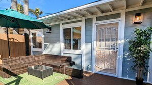 A covered outdoor seating area with wicker furniture and a green mat. - Extended Stay! 2 Bedroom/1 bath/Sleeps 6 (Vista)