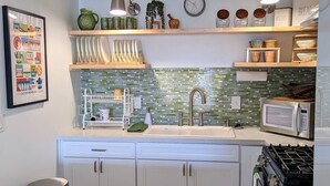 A modern kitchen with white cabinets, a stainless steel trash can, a microwave, and a stove. - Extended Stay! 2 Bedroom/1 bath/Sleeps 6 (Vista)