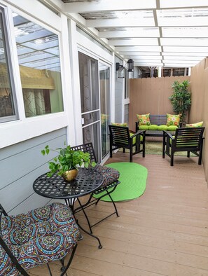 Eine überdachte Terrasse mit Tisch und Stühlen, einem Blumentopf und einem Holzzaun.