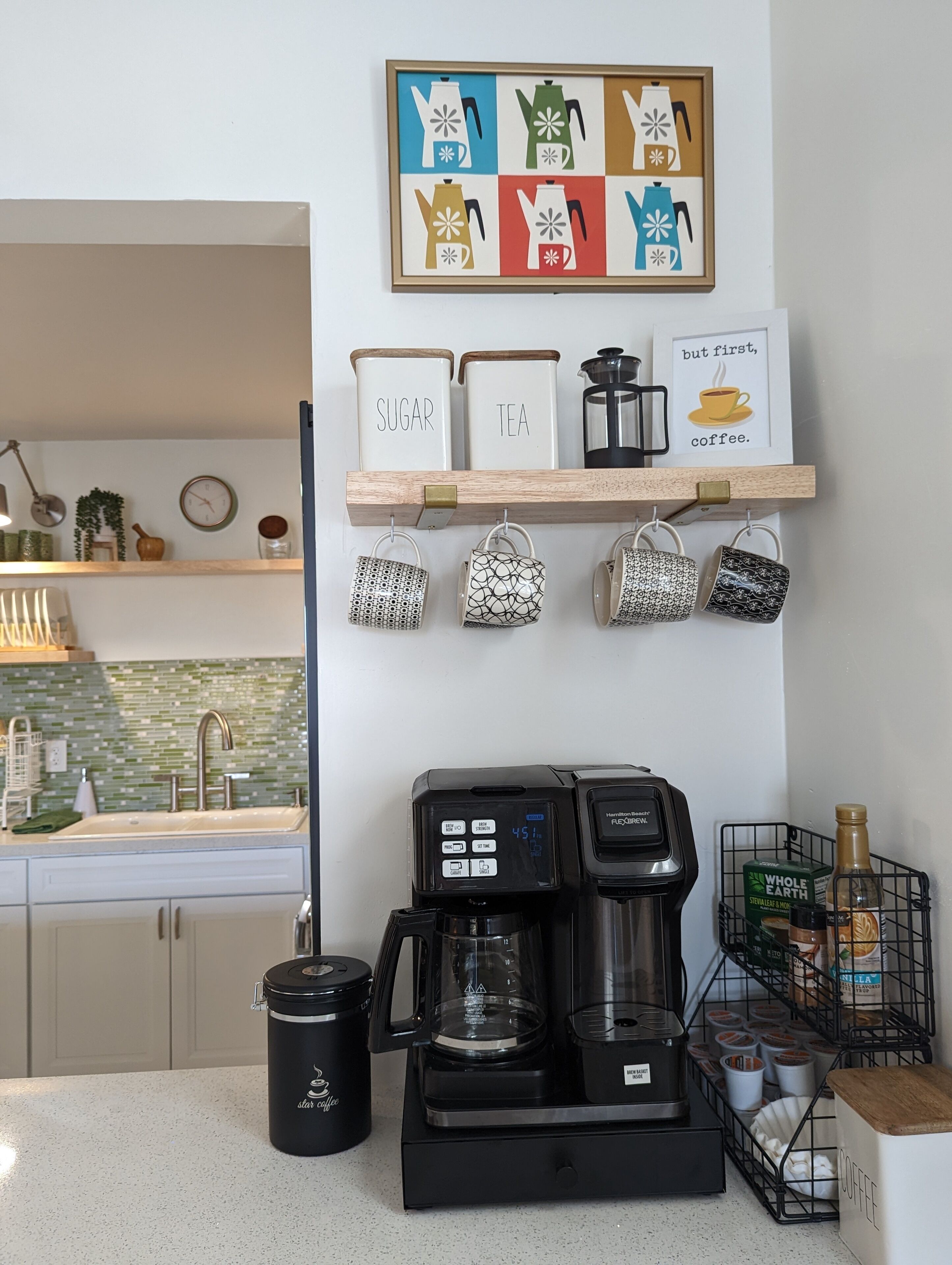Une cuisine équipée d’une machine à café, de pots à sucre et à thé, ainsi que d’une étagère décorée sur le thème du café.