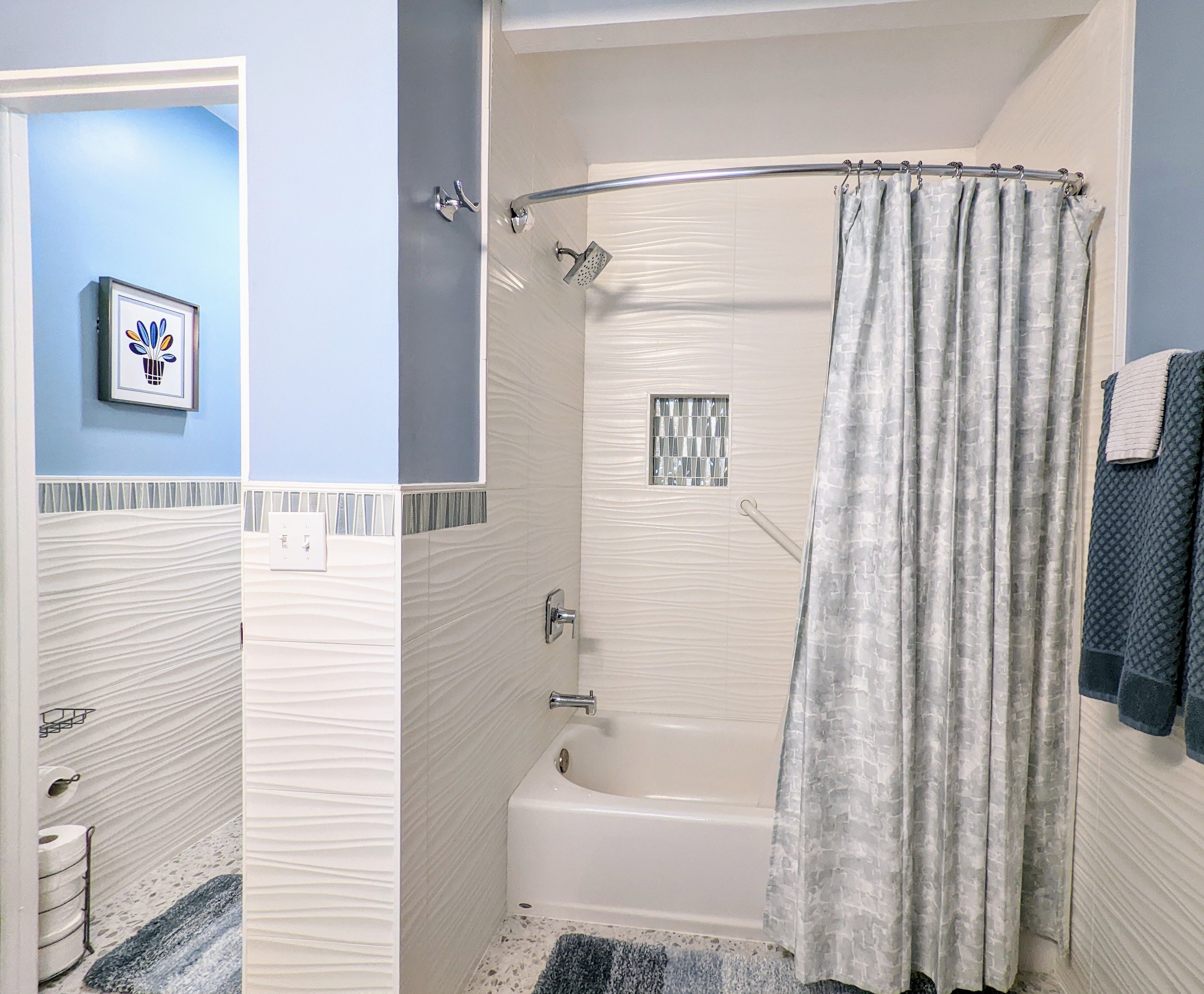 A bathroom with a bathtub, shower, and a towel rack.