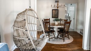 A dining area with a round table, wooden chairs, a hanging chair, a chandelier, and a painting on the wall. - High Point House - amazing location -Sleeps 12! (Memphis)