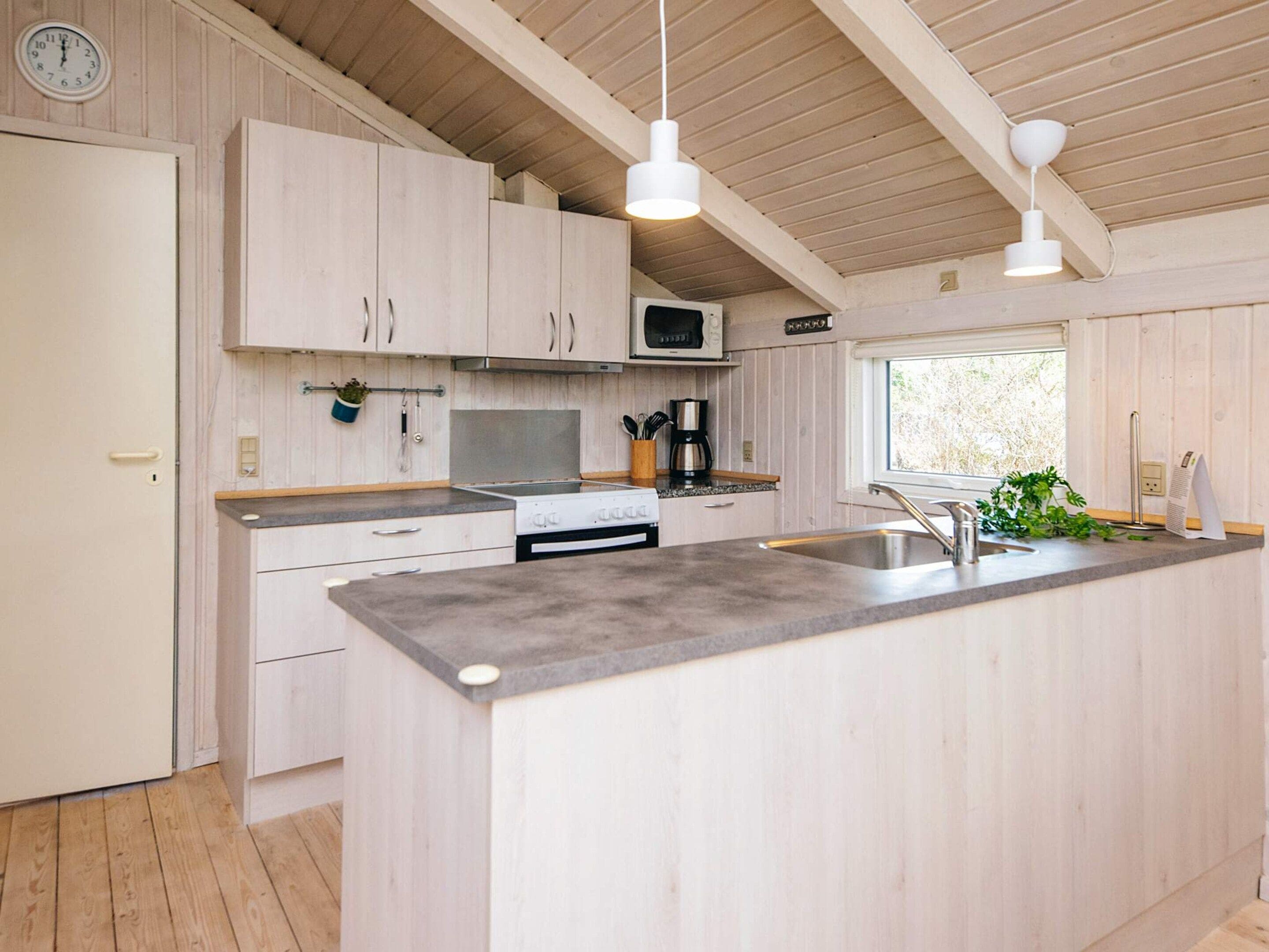 A modern kitchen with wooden cabinets, a central island, stainless steel appliances, and pendant lighting.