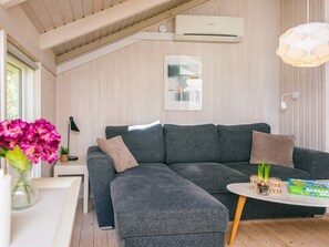 A modern living room with a sectional sofa, a round coffee table, and a wall-mounted air conditioner. - 6 Person Holiday Home in Ulfborg (Ulfborg)