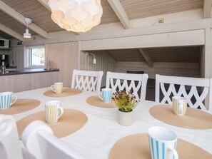 A dining area with a table set for four, white chairs, and a hanging light fixture. - 6 Person Holiday Home in Ulfborg (Ulfborg)