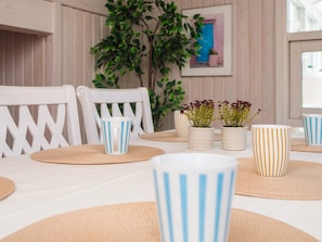 A dining table with striped cups, woven placemats, and potted plants. - 6 Person Holiday Home in Ulfborg (Ulfborg)