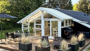 Una casa moderna amb terrassa, mobiliari exterior i plantes en testos.