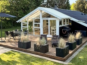 A modern house with a deck, outdoor furniture, and potted plants.