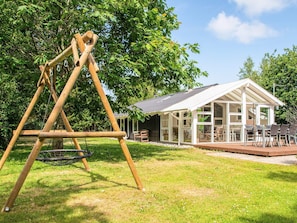 A wooden swing set and a glass-enclosed building with outdoor furniture. - 6 Person Holiday Home in Ulfborg (Ulfborg)
