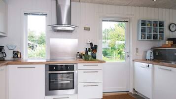 Una cocina moderna con armarios blancos, electrodomésticos de acero inoxidable y vistas al exterior.